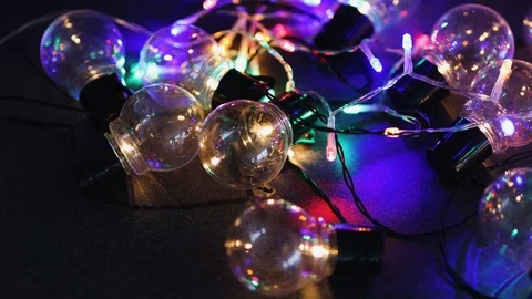 Group of lightbulb shaped string lights shining on dark desk with psychedelic Stock Footage 116646408