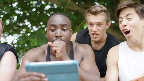 Group of male friends react to something they see on a digital tablet Stock Footage 91580868