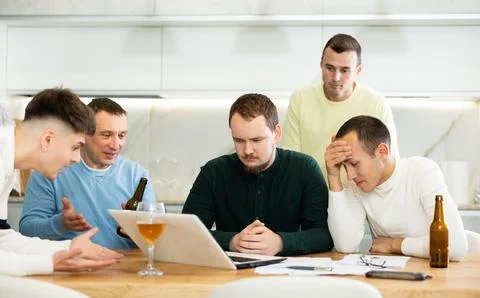 Group of male friends solving problems using laptop and drinking beer 写真素材