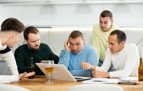 Group of male friends solving problems using laptop and drinking beer Stock Photos