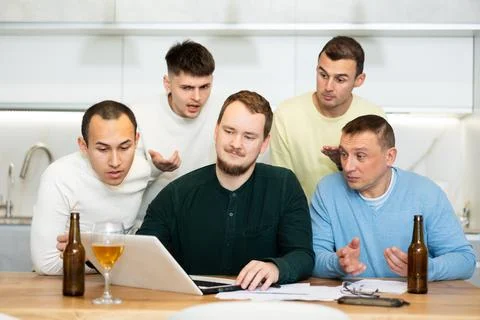 Group of male friends solving problems using laptop and drinking beer Stockfoto's