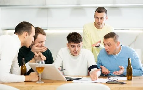 Group of male friends solving problems using laptop and drinking beer Stock Photos