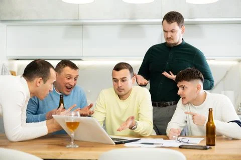 Group of male friends solving problems using laptop and drinking beer Foto stock