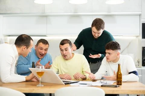 Group of male friends solving problems using laptop and drinking beer 写真素材