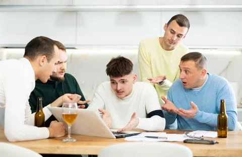 Group of male friends solving problems using laptop and drinking beer 写真素材