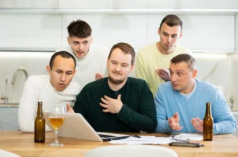 Group of male friends solving problems using laptop and drinking beer 写真素材