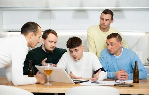 Group of male friends solving problems using laptop and drinking beer Fotos de archivo