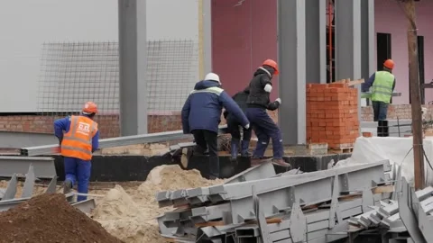 A group of male workers in yellow jackets and helmets is on the construction Stock Footage 132201289