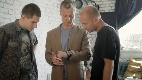 A group of man is discussing an app using smartphone in the office. Man is Stock Footage 90491883