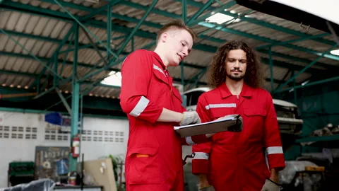 Group of mechanics consulting or checking a repairing a car lifting equipme.. Stock Footage 242833917