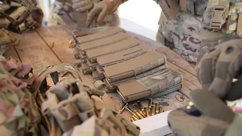A group of men are loading machine gun magazines with cartridges 库存影片 334492404
