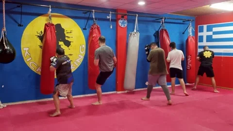 Group of men doing intense kickboxing workout hitting hanging red punch bags in Stock Footage 341727064