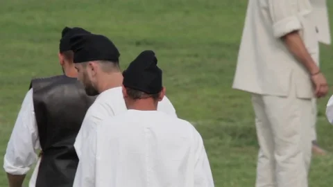 Group of men dressed in white, going on a green pasture Stock Footage 71341110