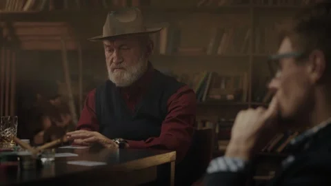 A group of men enjoying time playing cards in a dimly lit bar while sipping on Stock Footage 317678510