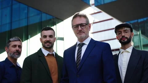 A group of men in suits, sharing a smile, stand in front of a building Stock Footage 266320947
