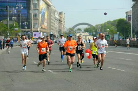 Group of men in tracksuits running down the street. Marathon among amateurs Stock Photos