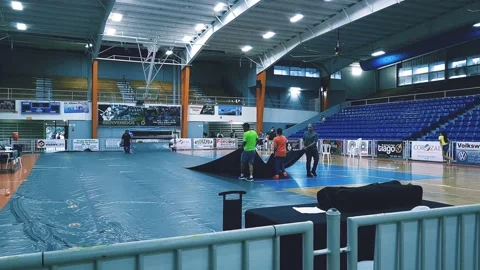 Group of Men Unloading a Big Floor Mat at Volleyball Coliseum Event Stock Footage 221665929