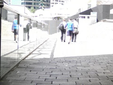 Group of men walking away from camera into white light past a glass barrier Stock Photos