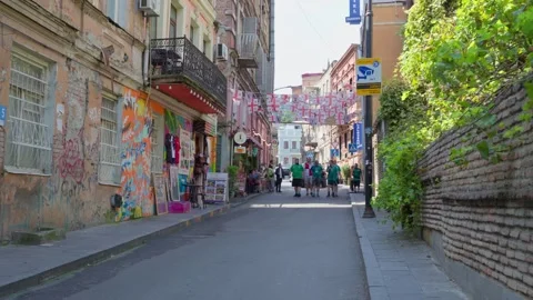 Group of men walking through a historic street in Tbilisi decorated with na.. Video stock 346545731