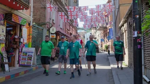 Group of men walking through a historic street in Tbilisi decorated with na.. Video stock 346545987