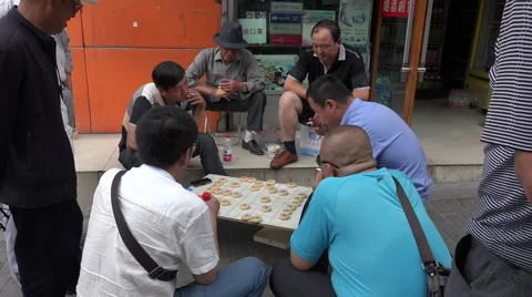 Group of men watching a game of Chinese Chess game on sidewalk Stock Footage 47455558