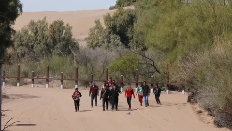 Group of Mexican migrants walking through scrubland at southwest border Stock Footage 106117348