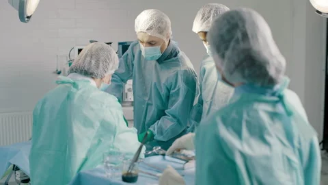 A group of mixed-race surgeons and nurses work together in an operating room Video stock 280109891