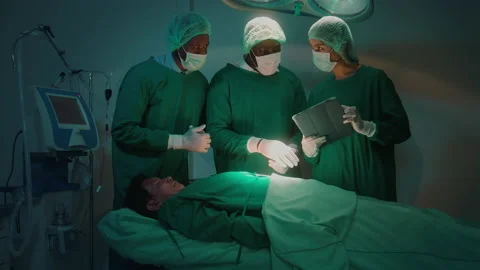 Group of mixed-races professional surgeons operating in hospital operating ro Видео 195208587