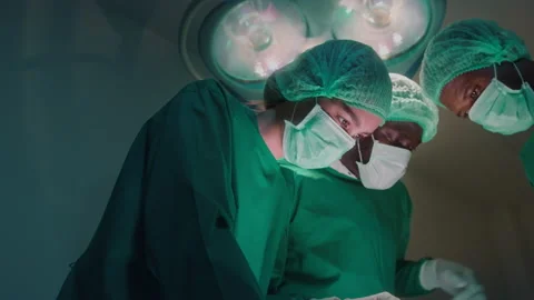 Group of mixed-races professional surgeons operating in hospital operating ro Видео 195209560