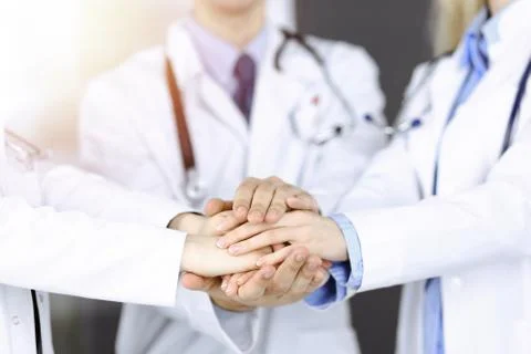 Group of modern doctors joining hands as a circle. Teamwork in medicine during Stockfoto's