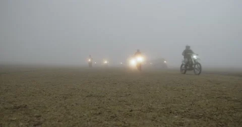 Group of motorcycles rides through a field in fog Stock Footage 232138769