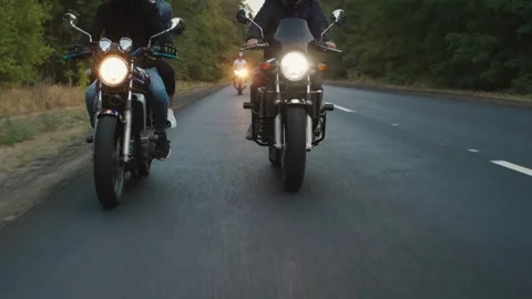 Group of motorcyclists riding along forest road at sunset in cinematic motion Stock Footage 335063016