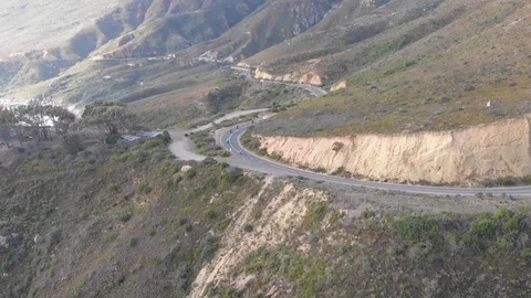 A group of motorcyclists riding down a winding mountainous road next to the s Stock-Footage 100702827