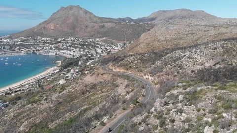 A group of motorcyclists riding down a winding mountainous road next to the s Stock-Footage 100703191