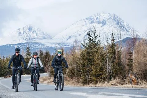 Group of mountain bikers riding on road outdoors in winter. Stock Photos