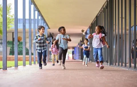 Group Of Multi-Cultural Elementary School Pupils Running Along Walkway Outdoors Stock Photos