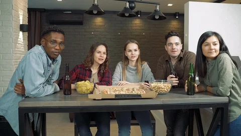 Group of multi-ethnic friends drinking beer and watching TV together at home Video stock 124052058