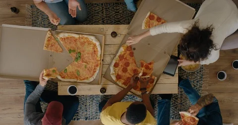 Group of multi ethnic friends eating pizza enjoying meal together sharing Stock Footage