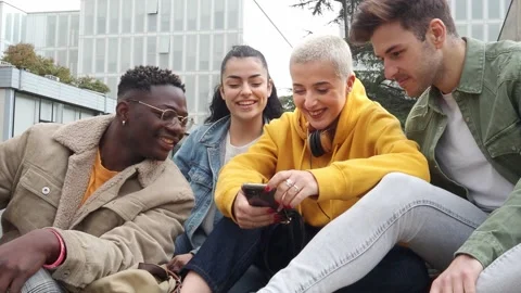 Group of multi-ethnic students sitting in a campus looking at mobile phone Stock Footage 171868063