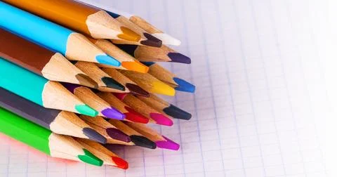 Group of multicolor pencils on white checkbook in a cage , close up shot Stock Photos