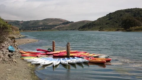 Group of multicolored kayaks at Russian River facing south in Jenner, California Video stock 79549686