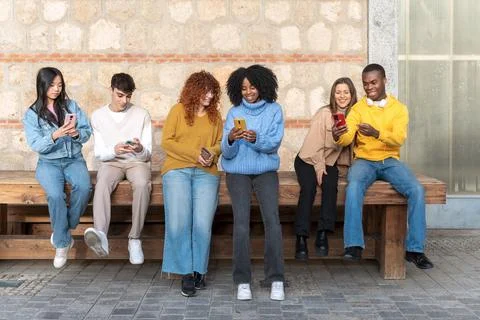 Group of multiethnic friends using their mobile phones together. 스톡 사진