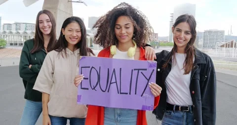Group of multiethnic girls looking at camera holding a sign that says: Equality Stock Footage 219486988