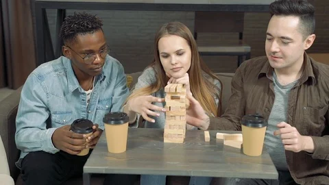 Group of multinational friends playing block removal game in the living room Stock Footage 123148424