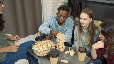 Group of multinational friends playing block removal game in the living room Stock Footage 123151756