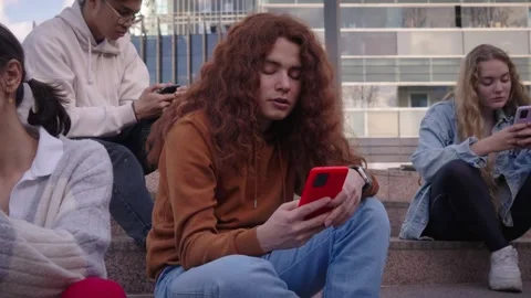 Group of multiracial classmate students looking at their smartphones sharing Stock Footage 247798480