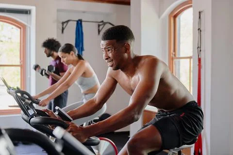 Group of multiracial young adults doing cardio on exercise bike at the gym Stock Photos