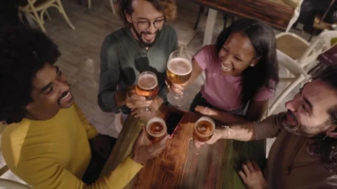 Group of multirracial young people toasting with a pint of beer and celebrating Stock Footage 243677859