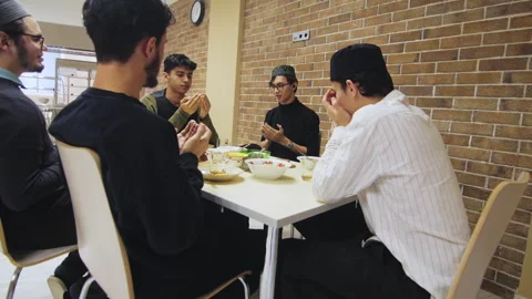 Group of Muslim men pray before eating meal sitting at table Stock Footage 257565746