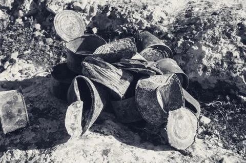 Group of old rusty tin cans covered with ash on stones at sunny day Stock Photos